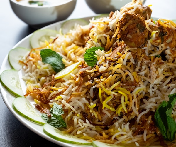 Close-up of Hyderabadi dum biryani in a clay handi with fried onions, egg and steam rising