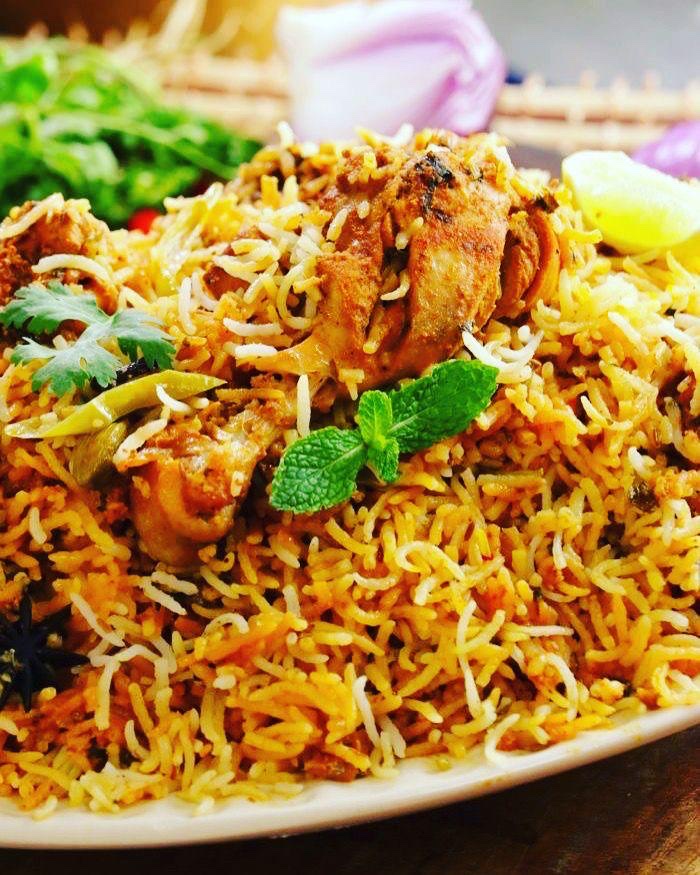 A generously plated serving of chicken dum biryani garnished with fresh mint, coriander and lemon