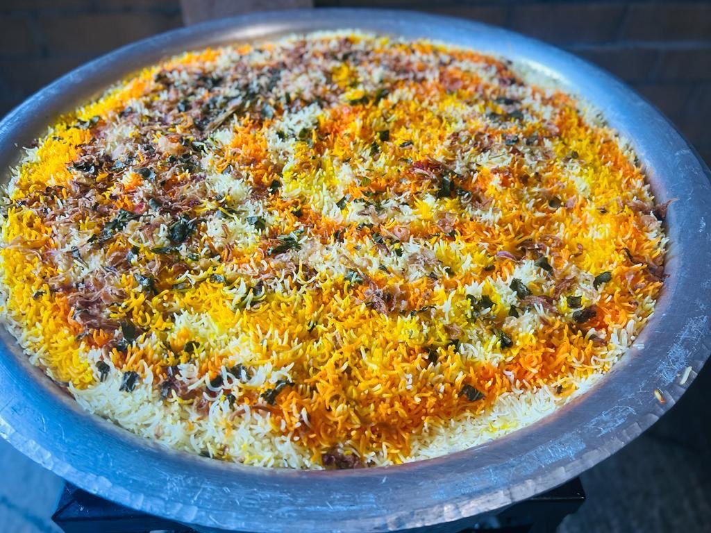 A large catering tray of garnished biryani prepared for a bulk order