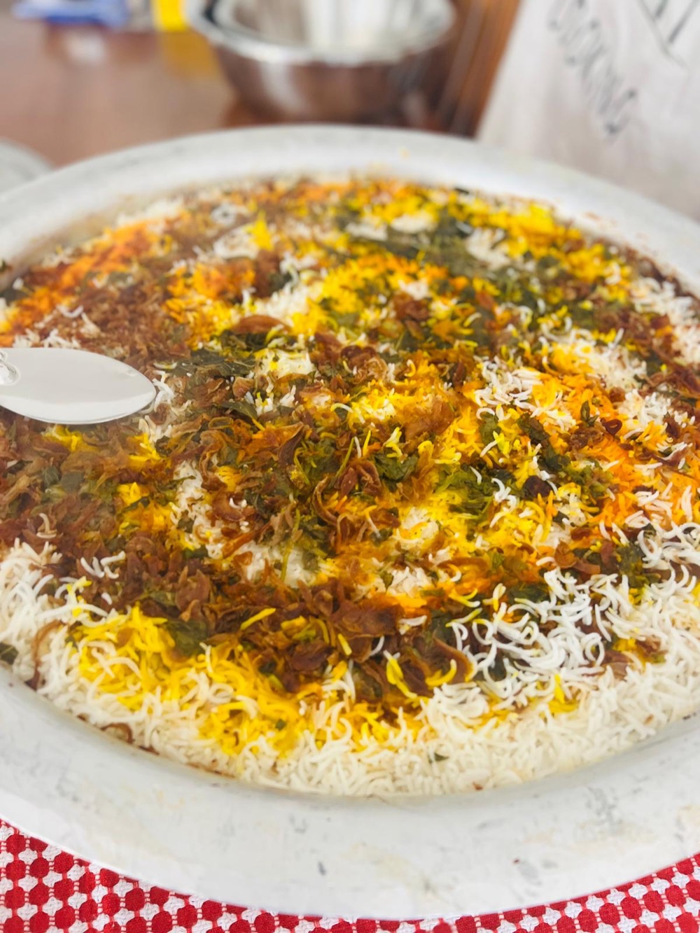 A caterer serving biryani from a large tray at an event